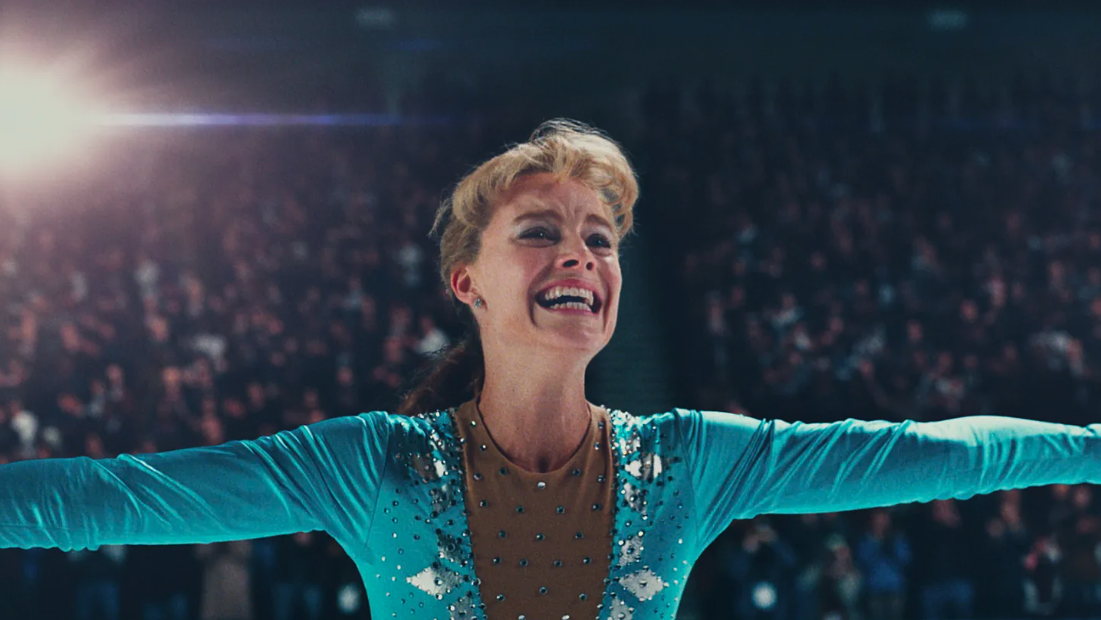 Margot Robbie as Tonya Harding opens her arms out wide on the ice